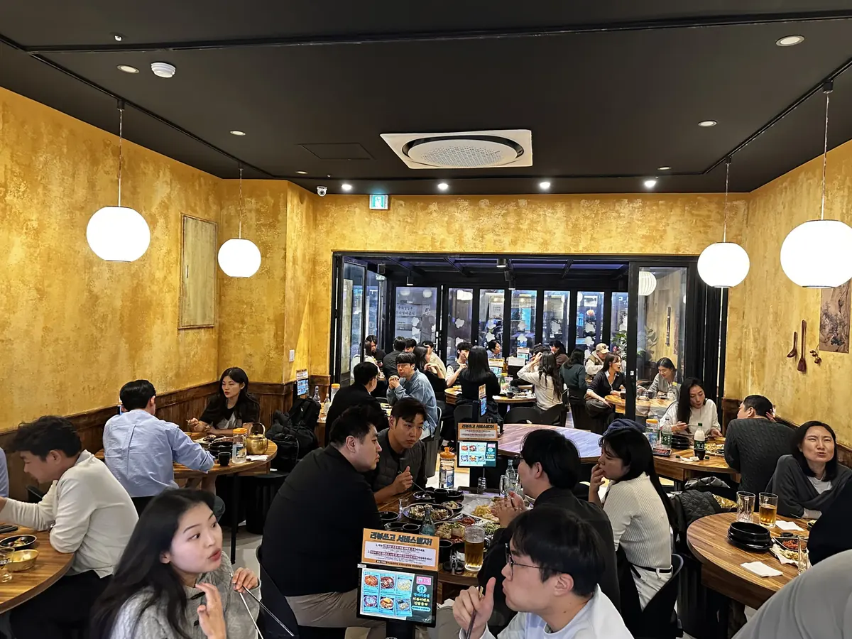 원목 테이블과 조명이 있는 할매기름집 홀 전경